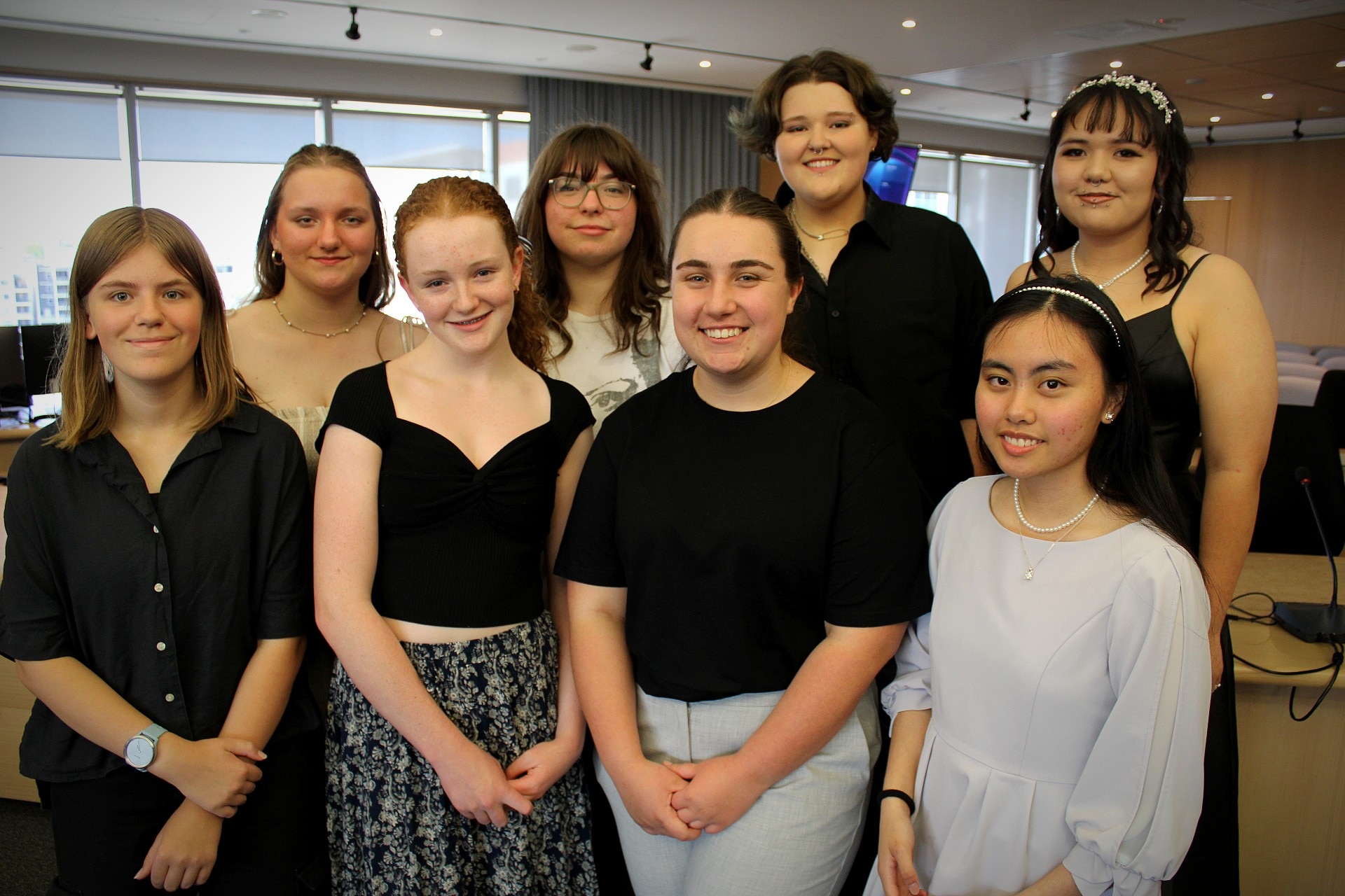 Eight high school students pictured in two rows of conference room