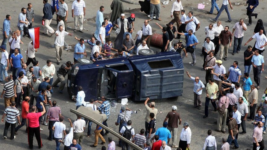 Muslim brotherhood supporters of Mohammed Morsi overturn a police vehicle during clashes.