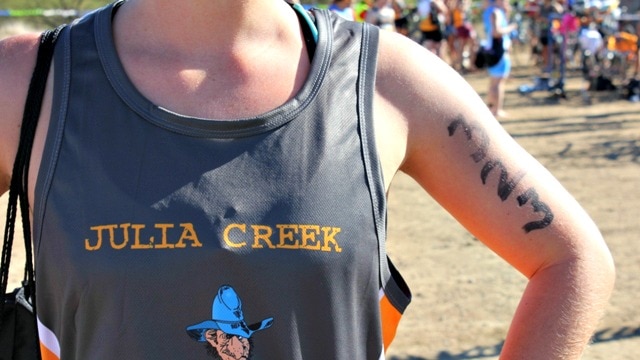 A singlet with Julia Creek written on it above a cartoon of a triathlon competitor wearing a blue cowboy hat.