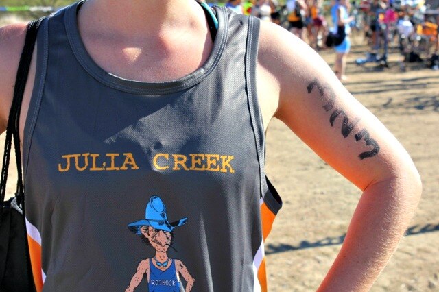 A singlet with Julia Creek written on it above a cartoon of a triathlon competitor wearing a blue cowboy hat.