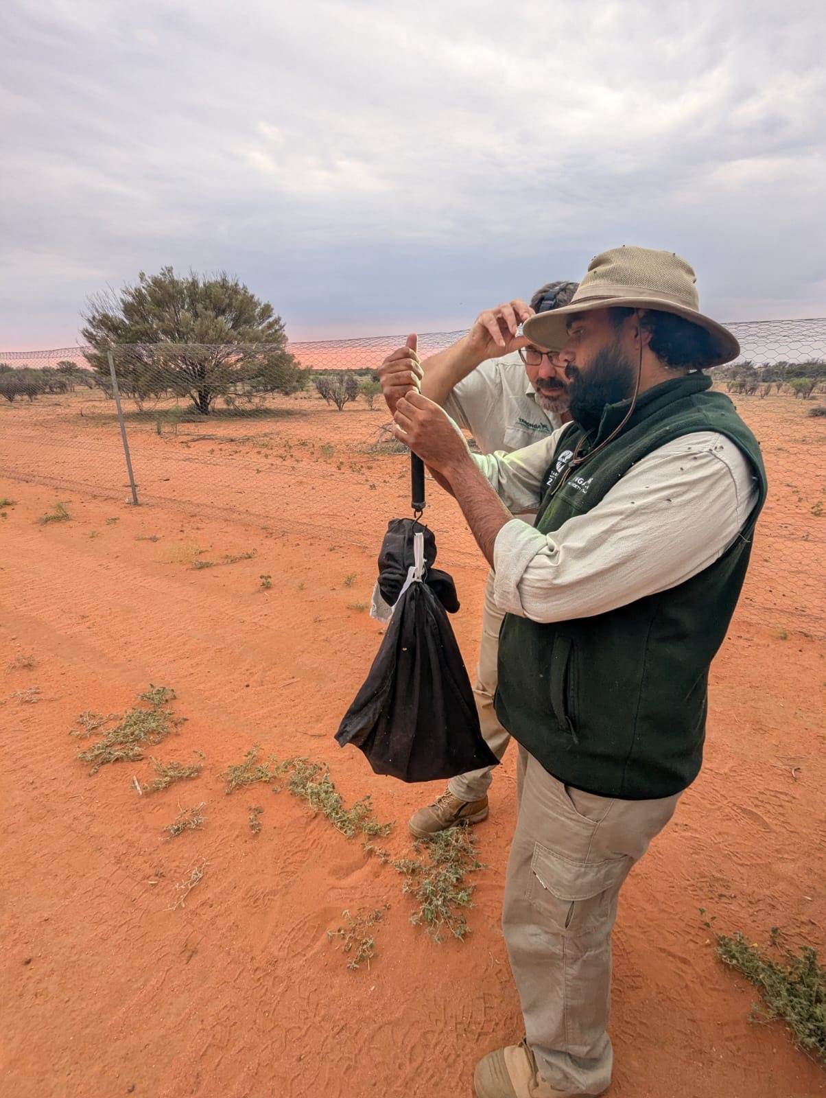 Dos hombres hablan entre sí y sostienen una bolsa en la mano.