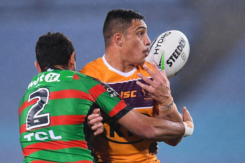 Brisbane Broncos player Kotoni Staggs is tackled by South Sydney Rabbitohs' Alex Johnston as the ball flies behind them.