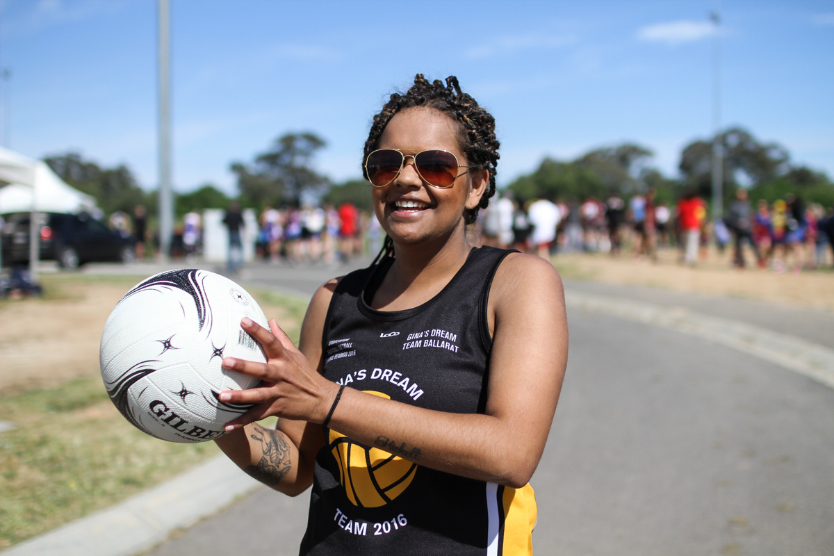 Jordan Kickett, 23, from Gina's Dream Team from Ballarat is holding a netball and smiling at the camera.