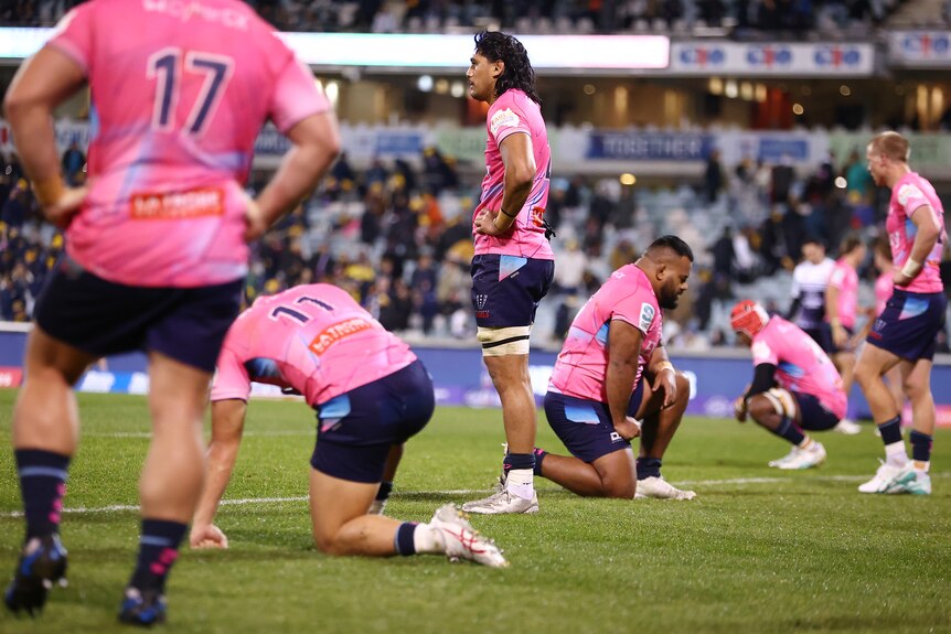 Melbourne Rebels players look sad during a Super Rugby game.
