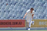 A young men's fast bowler is pictured in his follow-through from a delivery as the ball flies down the pitch.  