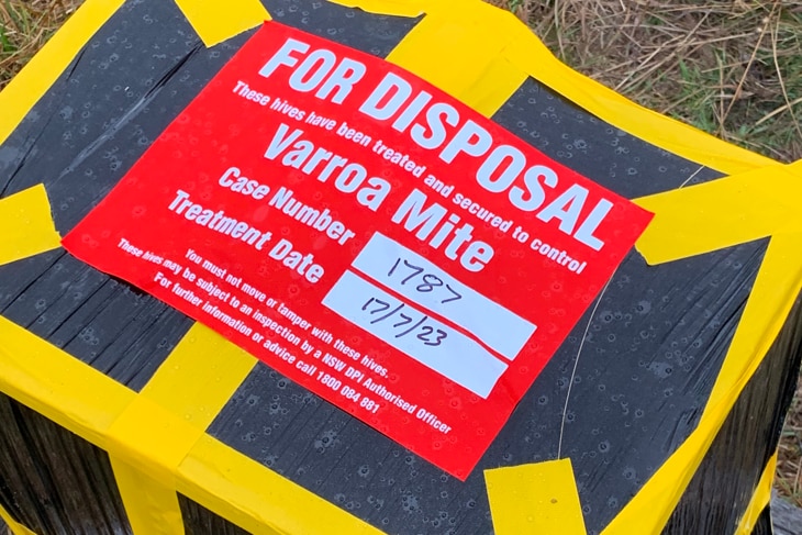 A beehive wrapped in black plastic and yellow tape, bearing a red sign that reads "For Disposal".