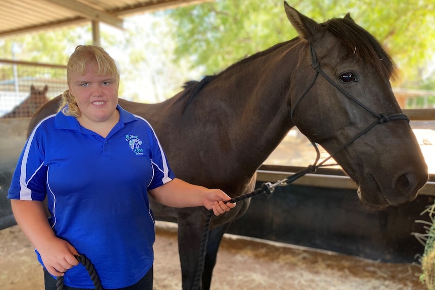 Woman standing next to horse in stables