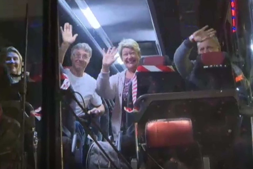 Travellers wave from the bus