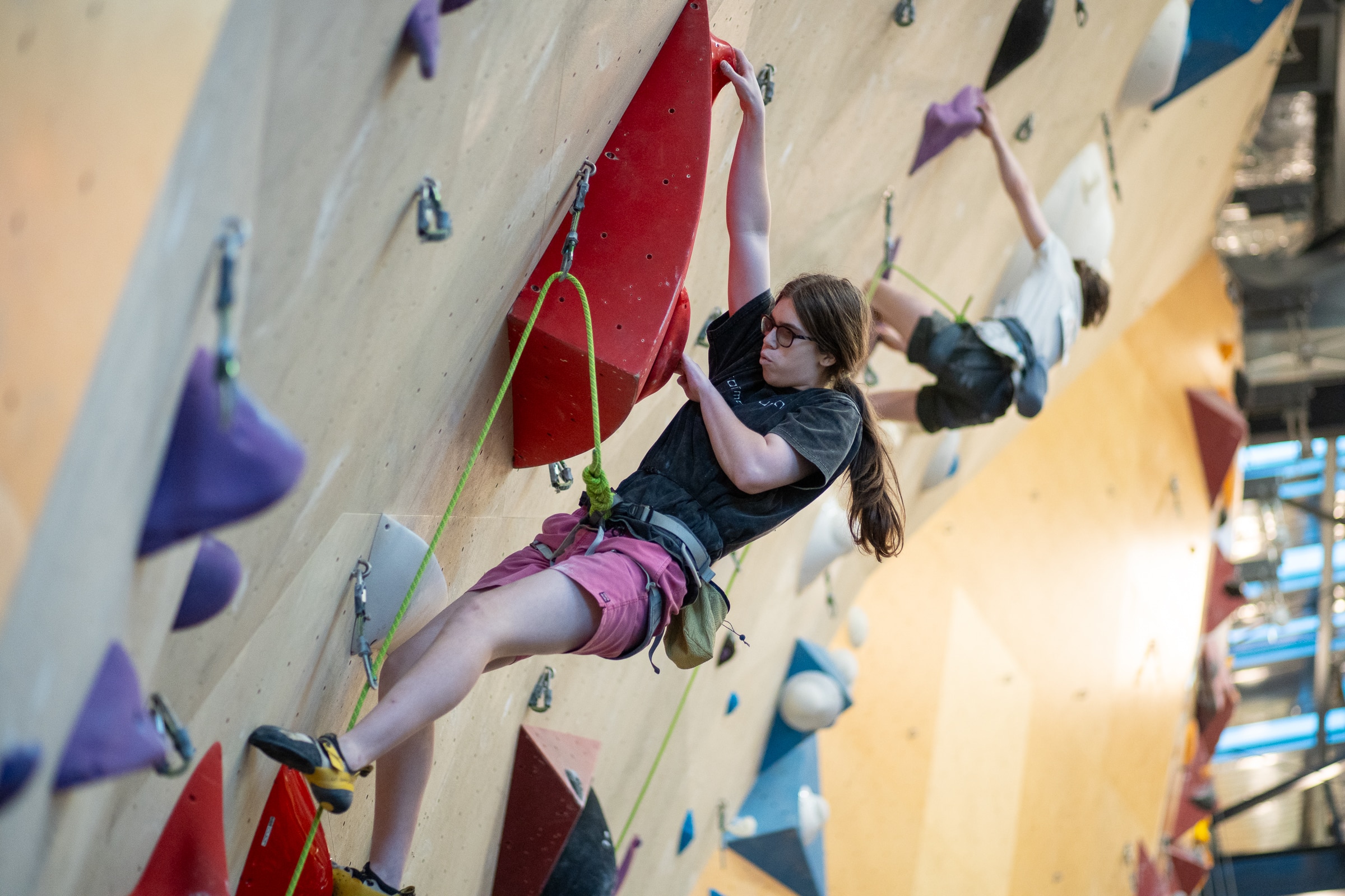 A young woman is climbing an indoor rock climbing wall.