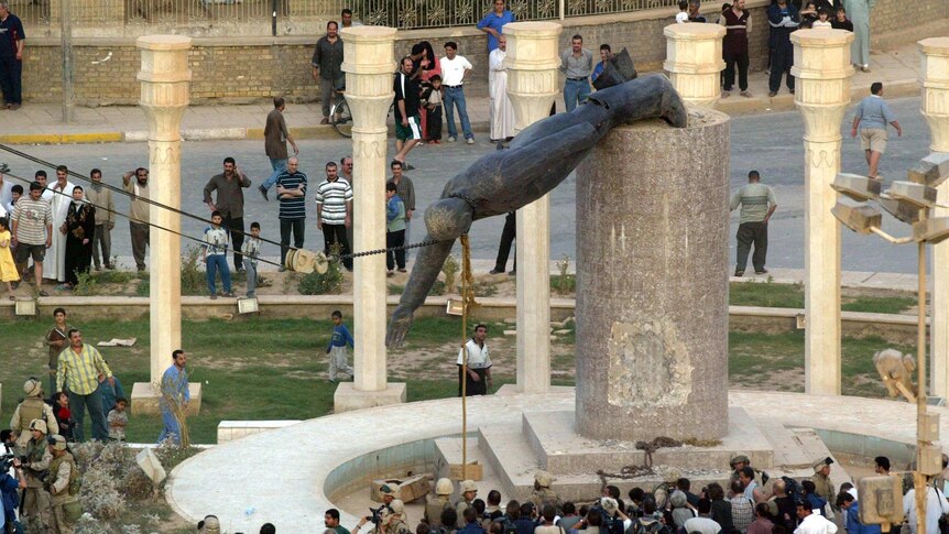 Iraqis watch the statue of Saddam Hussein fall in Baghdad's al-Fardous square on April 9, 2003.