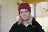 A woman with a red beanie and long blonde hair looking at the camera