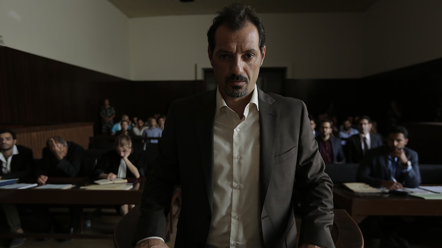 Still image of a serious looking Adel Karam standing before a courtroom in 2018 film The Insult.