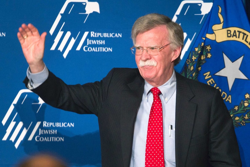 Man wearing a suit waves at the crowd.