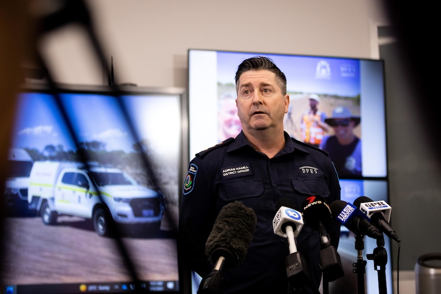 Adrian Hamill pictured in front of screens wearing his official DFES uniform while addressing the media