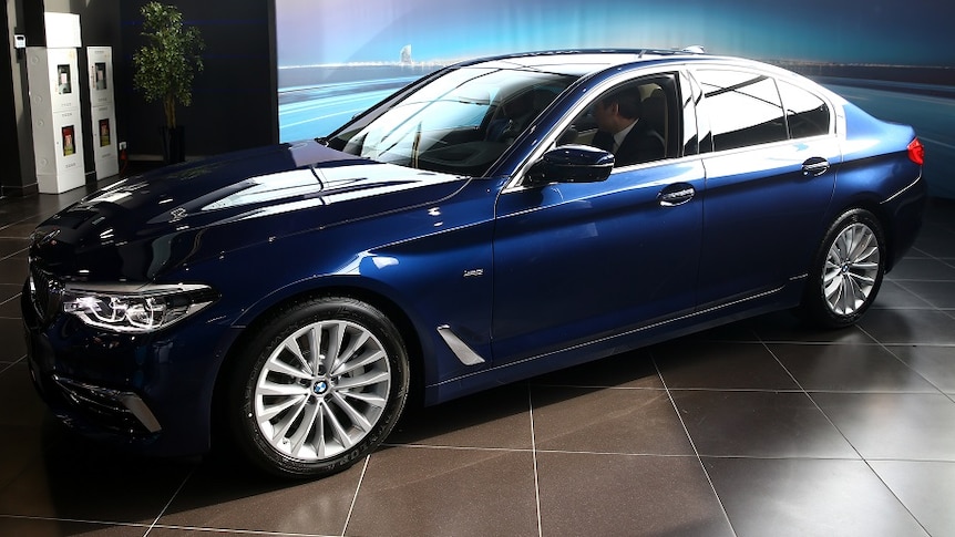A navy blue luxury sedan is displayed in a showroom