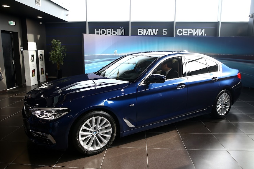 A navy blue luxury sedan is displayed in a showroom