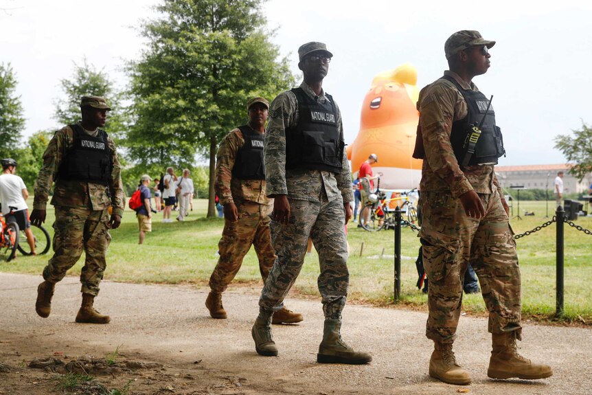 National Guard walk near a baby Trump balloon