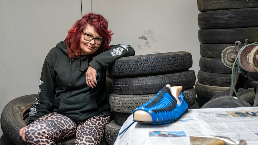 Shoemaker Pamela Gower sitting on a pile of tyres.