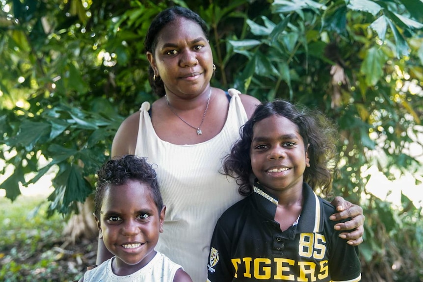 Kenisha Gumbala stands in the garden, with two of her younger family members, at home in Darwin.
