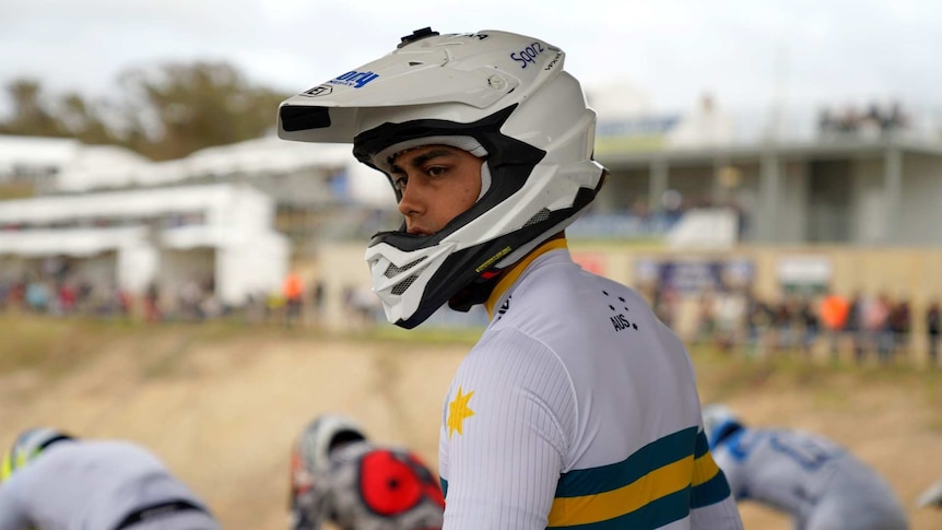 A young man in Australian sports colours and helmet.