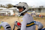 A young man in Australian sports colours and helmet.