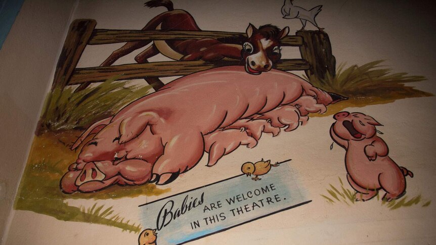A wall mural of a pig with piglets and a sign saying babies are welcome in this theatre