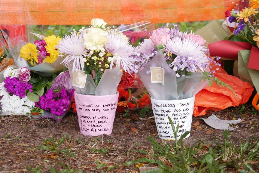 A close up of two flower bunches with notes written to the victim.