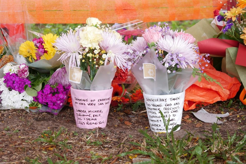 A close-up of two flower bunches with notes written to the victim.