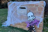 A mailbox with cobweb decorations and a "Happy Halloween" sign.