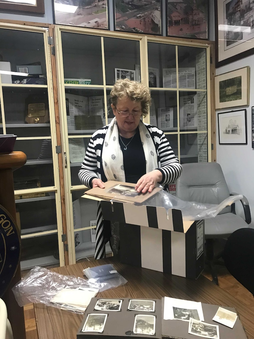 A woman with curly hair looking through a box of photos.