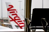 Virgin Australia logo on the tail of an aircraft looking out from inside an airport terminal.