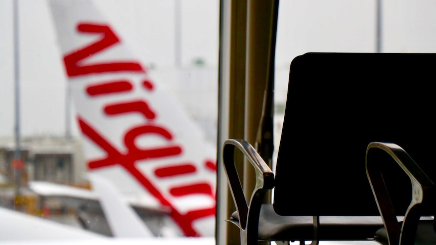 Virgin Australia logo on the tail of an aircraft looking out from inside an airport terminal.