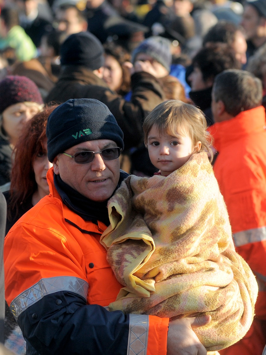 Rescue worker carries a child after ship disaster