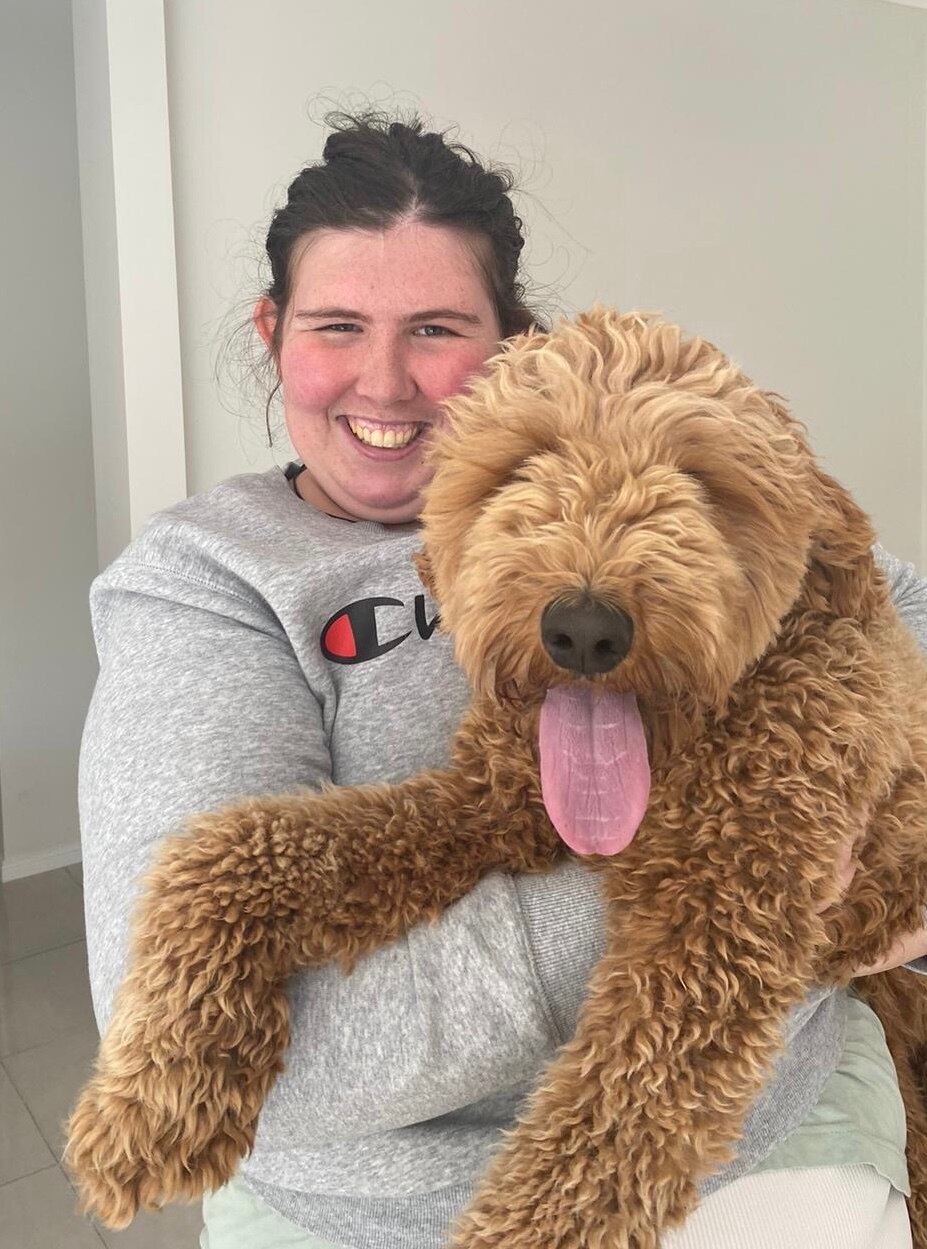 Jovem segura cachorro enquanto sorri