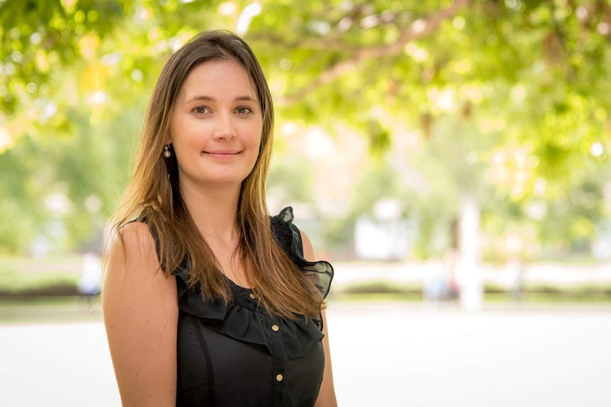 Dr Elena Schneider stands in front of trees