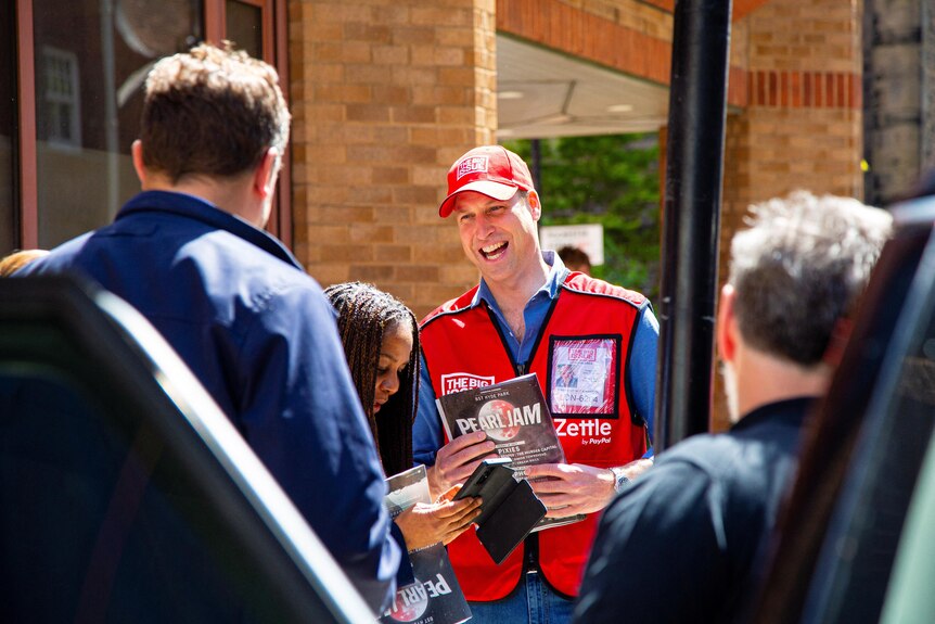 Britain's Prince William works as a vendor of The Big Issue newspaper on a street.