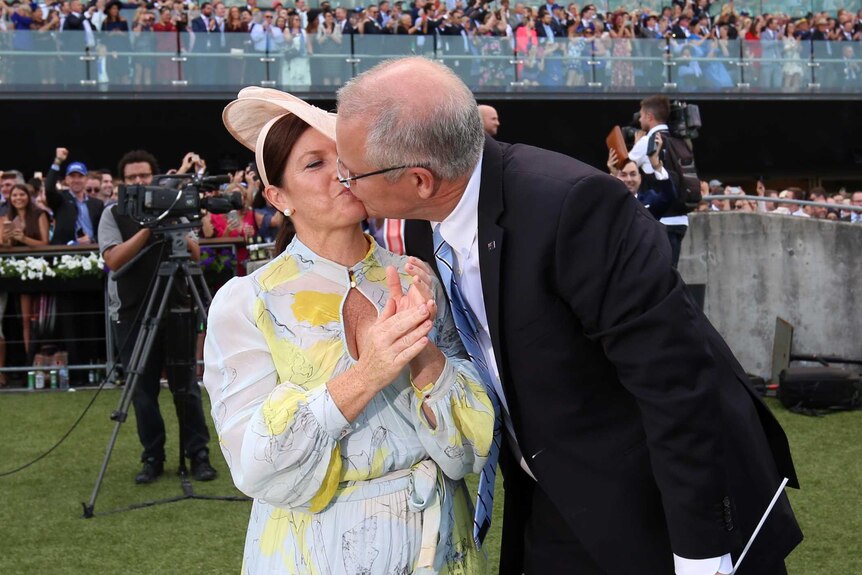 Prime Minister Scott Morrison and his wife Jenny kiss surrounded by racegoers