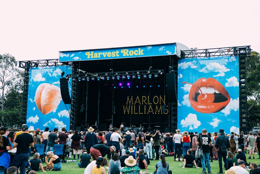 a big stage in a green field. the backdrop says MARLON WILLLIAMS and top banner says HARVEST ROCK