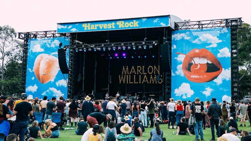 a big stage in a green field. the backdrop says MARLON WILLLIAMS and top banner says HARVEST ROCK