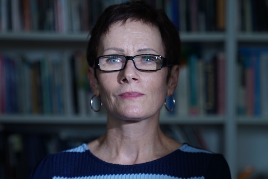 Professor Gail Mason stands in front of a bookshelf, she is a criminologist who researched the Bias Crimes Unite of NSW Police.