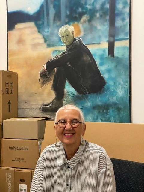 Woman smiling in front of portrait of man sitting on curb
