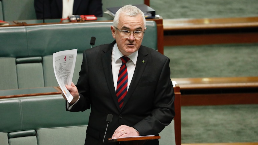 Wilkie stands in parliament holding up several pieces of paper.
