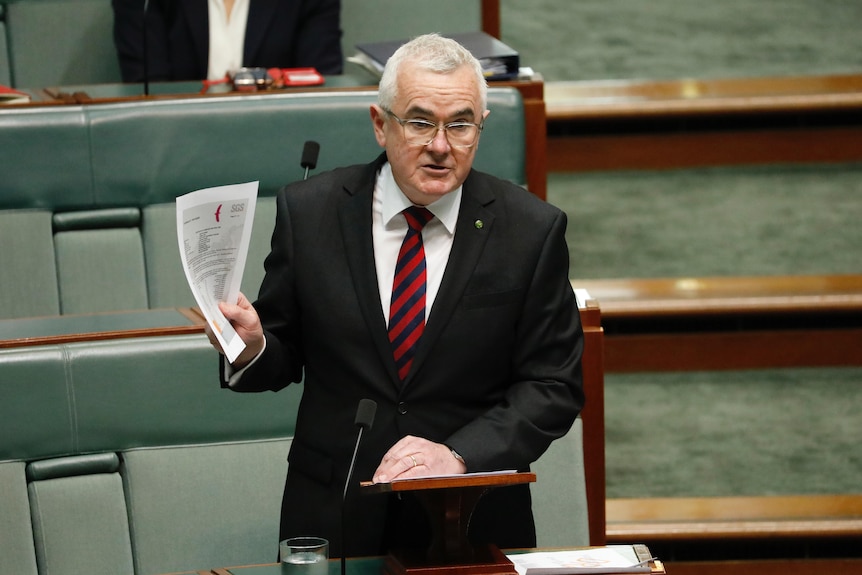 Wilkie stands in parliament holding up several pieces of paper.