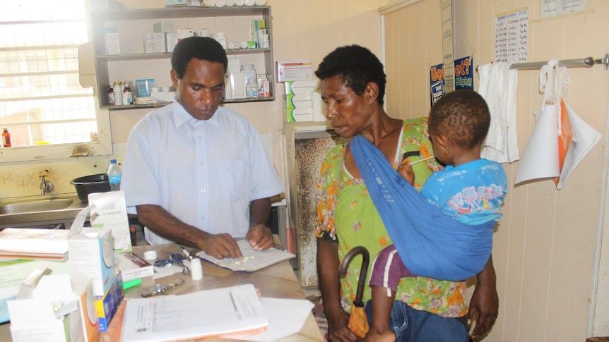A church health worker gives medicine to a woman and a baby at a clinic.