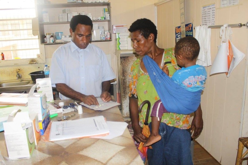 A church health worker gives medicine to a woman and a baby at a clinic.