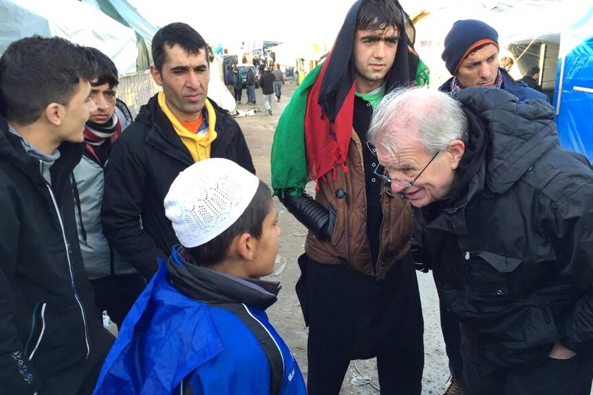 Reverend Bill Crews bends over to speaks with a 13-year-old refugee at the camp.