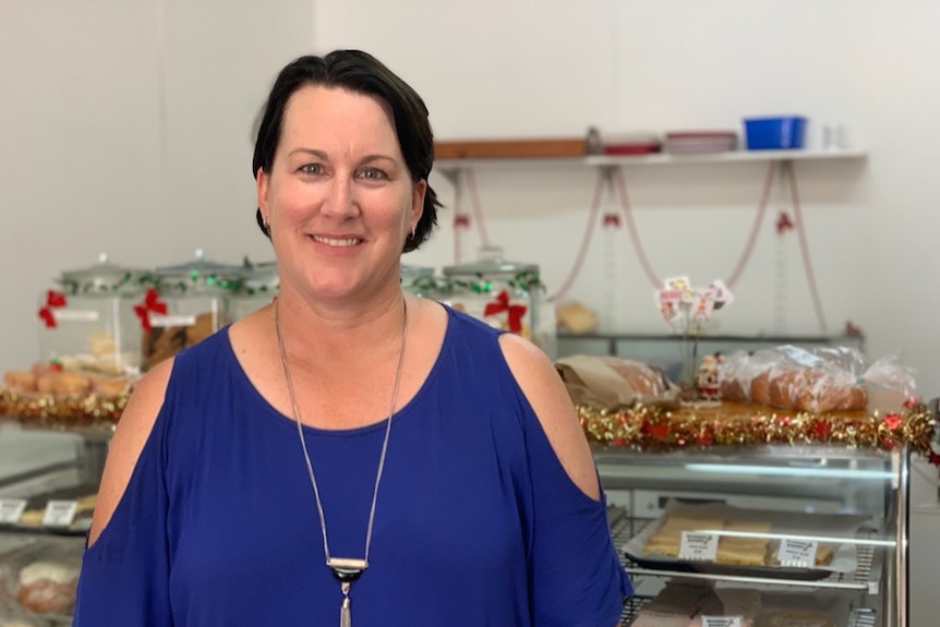 A smiling, dark-haired woman stands in a bakery.