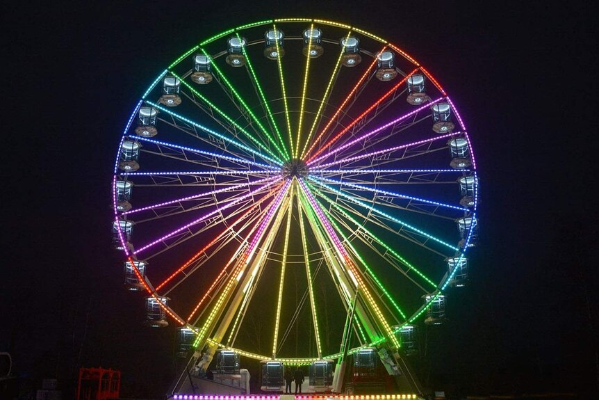 Australia's biggest moveable Ferris wheel lit up at night.