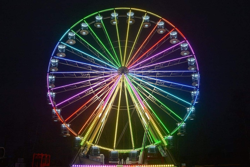 Australia's biggest moveable Ferris wheel lit up at night.