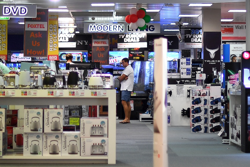 An electrical retail store with signs and products littered on the shop floor.